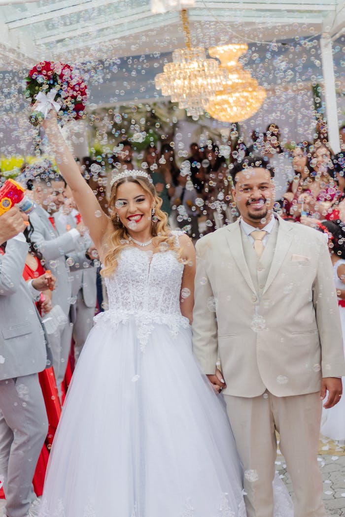 Bride and groom celebrating their wedding with cheerful guests and bubbles.