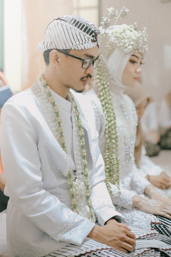 Bride and groom in traditional Indonesian attire during a wedding ceremony.